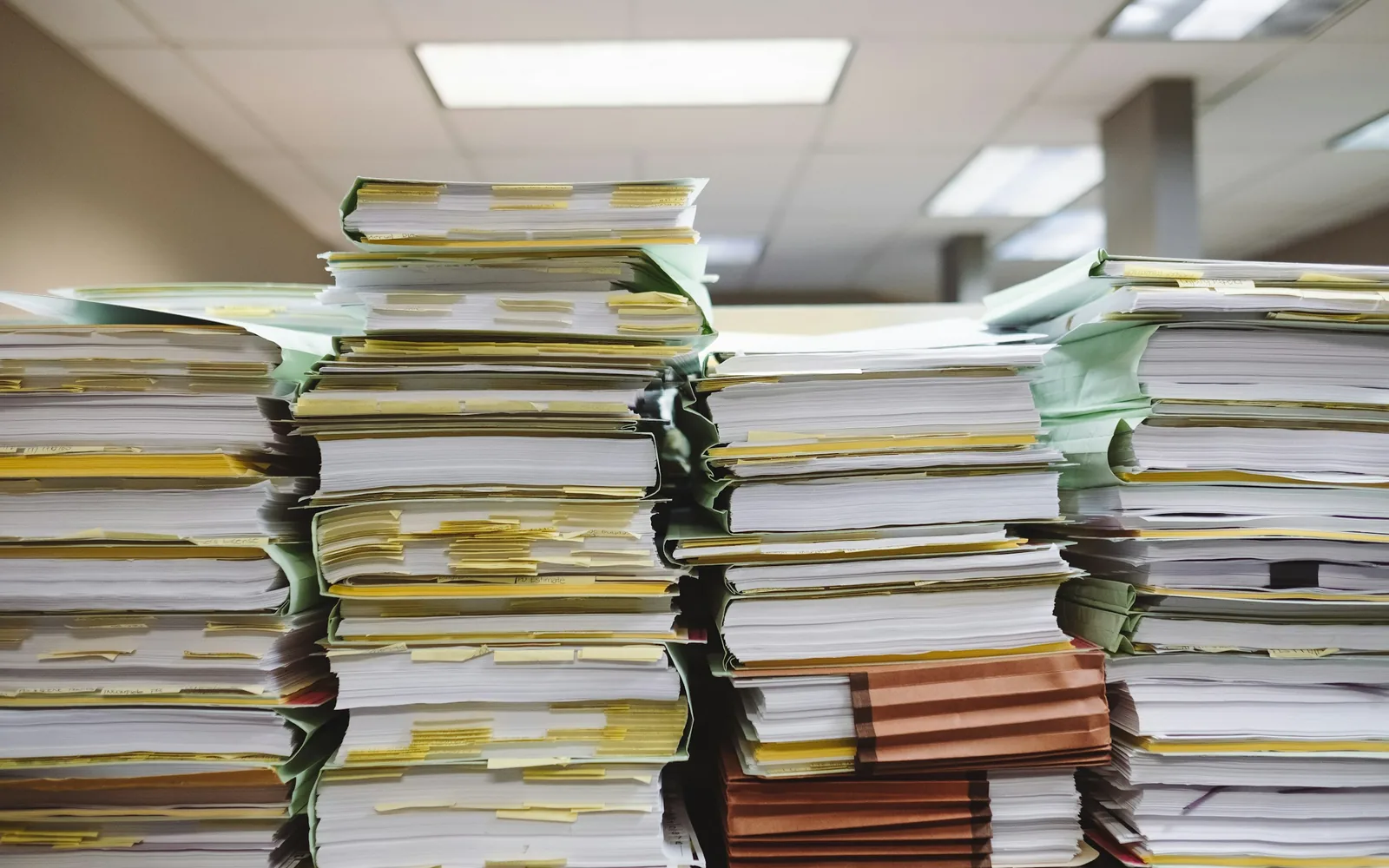 Stosy papierowych dokumentów i teczek ułożone na biurku